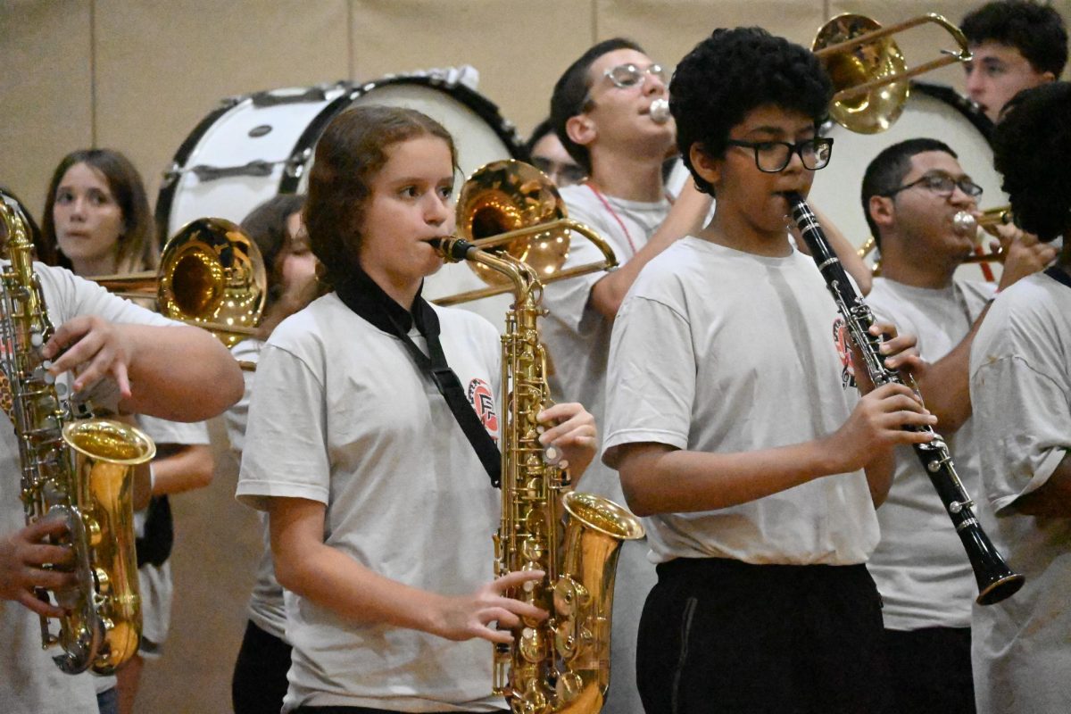 Omar Khalif (9) and Emily Collins (9) play their instruments in unison during Freedom's first pep rally of 2024-2025.